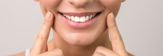 Nahansicht einer Frau, die auf Ihre weißen Zähne zeigt