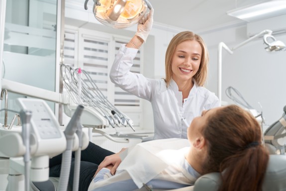 Zahnärztin lächelt Patientin zu während der Behandlung